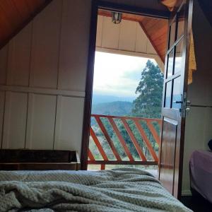 a room with a bed and a view of a balcony at Chalé das Margaridas in Rio Forcação