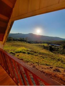 a view of a field from a porch with a window at Chalé das Margaridas in Rio Forcação