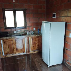 a kitchen with a white refrigerator and a brick wall at Chalé das Margaridas in Rio Forcação