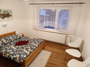 a bedroom with a bed and two chairs and a window at Domcek na orave in Habovka