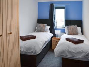 two beds in a room with blue walls at The Bandstand Sea View in Blythe