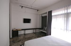 a bedroom with a bed and a tv on the wall at La Pause Hatyai in Hat Yai