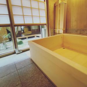 a large bath tub in a room with windows at Itsumoya in Miyajima