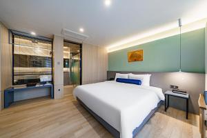 Un dormitorio con una gran cama blanca y una ventana en Hound Hotel Hadan, en Busan