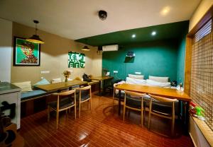 un restaurant avec des tables et des chaises et un mur vert dans l'établissement Guilin Cyan Box Guest House, à Guilin