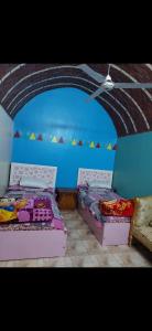 two beds in a room with a blue wall at Nuba life Mostafa Guesthouse in Najâ€˜ al MadÄbb