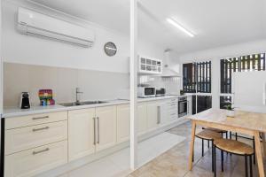 a kitchen with white cabinets and a wooden table at Urban Apartment in the Heart of Paddington in Brisbane