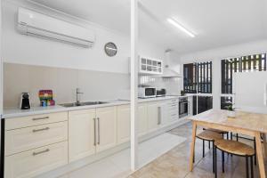 ブリスベンにあるUrban Apartment in the Heart of Paddingtonの白いキャビネットと木製のテーブルのあるキッチン