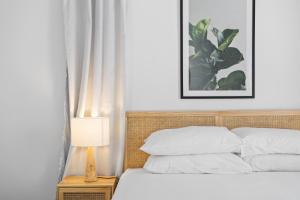 a bedroom with a bed with white sheets and a lamp at Urban Apartment in the Heart of Paddington in Brisbane