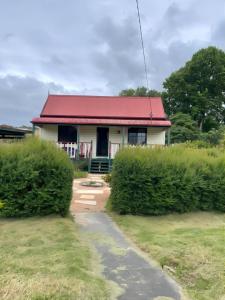 una casa con techo rojo y un camino que conduce a ella en Relaxing & beautiful Miner's cottage near Wilson’s Prom en Foster