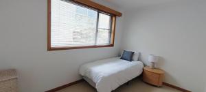 um pequeno quarto com uma cama e uma janela em Sweet home in Lenah Valley em Lenah Valley