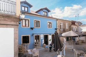 a blue building with an umbrella and tables and chairs at Blue House Ponte de Lima in Ponte de Lima