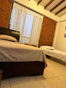 1 Schlafzimmer mit 2 Betten und einem Fenster in der Unterkunft Disfrute cabaña cálida, con piscina y zonas verdes in Viterbo