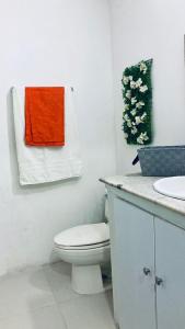 baño con aseo y lavamanos con toalla de color naranja en Acogedor Estudio 310 Cartagena Bocagrande a 1 cuadra de la playa, en Cartagena de Indias