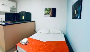 a small room with a bed with an orange blanket at Acogedor Estudio 310 Cartagena Bocagrande a 1 cuadra de la playa in Cartagena de Indias