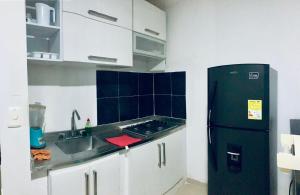 een keuken met een zwarte koelkast en een wastafel bij Acogedor Estudio 310 Cartagena Bocagrande a 1 cuadra de la playa in Cartagena