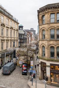 曼徹斯特的住宿－Deansgate Luxury Apartments，一条城市街道,前面有建筑和一辆面包车