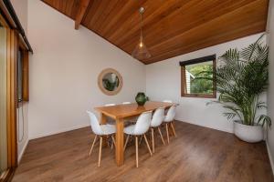 comedor con mesa de madera y sillas blancas en TJ's Tree House with Ocean Views, en Cape Schanck