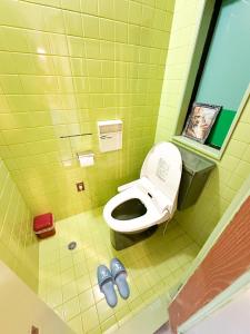 een badkamer met een toilet en twee paar schoenen bij ホテル亀岡 in Minamijō