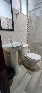 y baño con aseo y lavamanos. en Apartahotel San Isidro, en Monguí