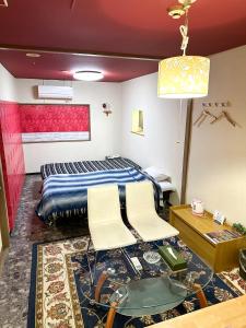 a bedroom with a bed and two white chairs at Hotel Rakusai in Kyoto