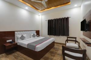 a bedroom with a bed and a chair and a television at Townhouse Hotel Trijal Inn in Lucknow