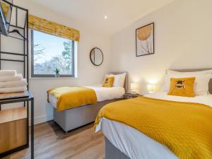 two beds in a room with yellow sheets at The Haywain in East Bergholt