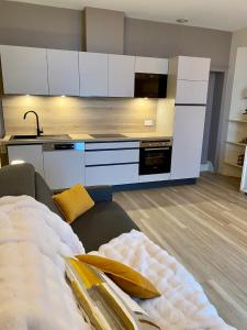 a kitchen with white cabinets and a couch in a room at Appartement ROCK WILL in Dinard