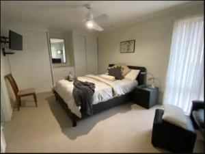 ein Schlafzimmer mit einem großen Bett und einem Stuhl in der Unterkunft Bob & Rob's Beach Retreat in Dalmeny