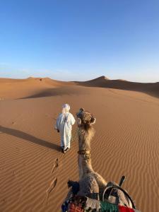 Un uomo e un cammello nel deserto di Bivouac Erg Chegaga Nomademoi a El Gouera