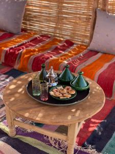 El GoueraにあるBivouac Erg Chegaga Nomademoiのベッドの上にテーブルと食べ物のトレイ