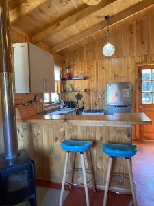 cocina con encimera y 2 taburetes de barra azul en Rumiloft Cabañas, en Valdivia