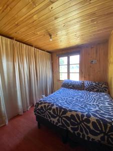 1 dormitorio con 1 cama en una habitación de madera en Rumiloft Cabañas, en Valdivia