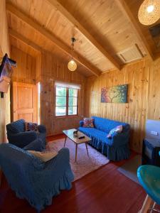 una sala de estar con sofás azules y una mesa. en Rumiloft Cabañas, en Valdivia