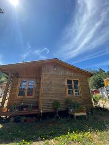 una pequeña casa de madera con un banco delante en Rumiloft Cabañas, en Valdivia