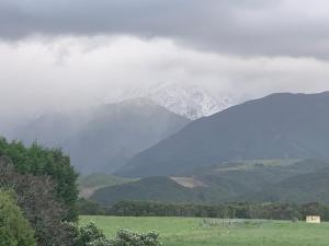 eine neblige Bergkette mit einem Feld und Bergen in der Unterkunft Kaikoura Mountain Views Villa in Kaikoura
