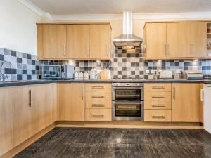 a kitchen with wooden cabinets and a stove top oven at Dunlin Haven in Sandside