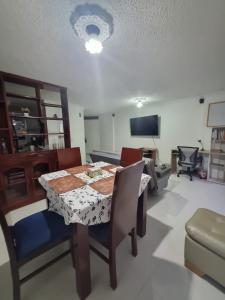 a dining room with a table and chairs and a television at Apartamento El Rosal in Ibagué