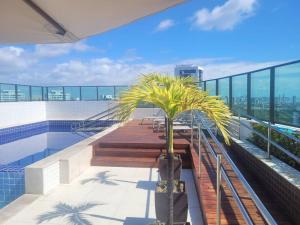 einen Balkon mit Bänken und einer Palme auf einem Gebäude in der Unterkunft Apartamento Flat em Boa Viagem in Recife