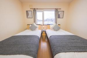 two beds in a room with a window at Kirin House in Furano +28 photos