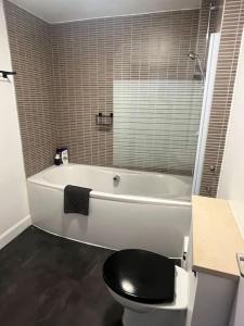 a bathroom with a white tub and a black toilet at Boyds Entry flat Old town in Edinburgh