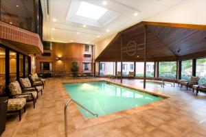 a pool in a building with chairs and tables at Ann Arbor Regent Hotel and Suites in Ann Arbor