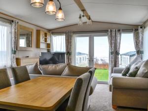 een woonkamer met een tafel en een bank bij Paul Jones Bay 63 - Uk46380 in Mainsriddle