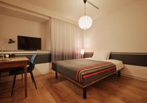 a bedroom with a bed and a desk and a television at Hotel Graphy Nezu in Tokyo