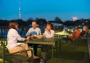 a group of people sitting at a table on a deck at Hotel Graphy Nezu in Tokyo