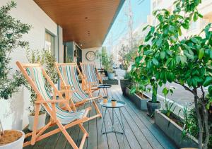 a row of chairs and tables on a porch with plants at Hotel Graphy Nezu in Tokyo