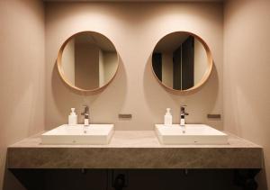 a bathroom with two sinks and two mirrors at Hotel Graphy Nezu in Tokyo