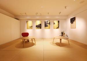 a room with two tables and paintings on a wall at Hotel Graphy Nezu in Tokyo