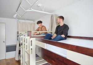 two men sitting on bunk beds in a room at Hotel Graphy Nezu in Tokyo