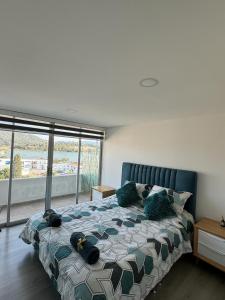 ein Schlafzimmer mit einem Bett und einem großen Fenster in der Unterkunft Rústico 804 Lago Sochagota in Paipa